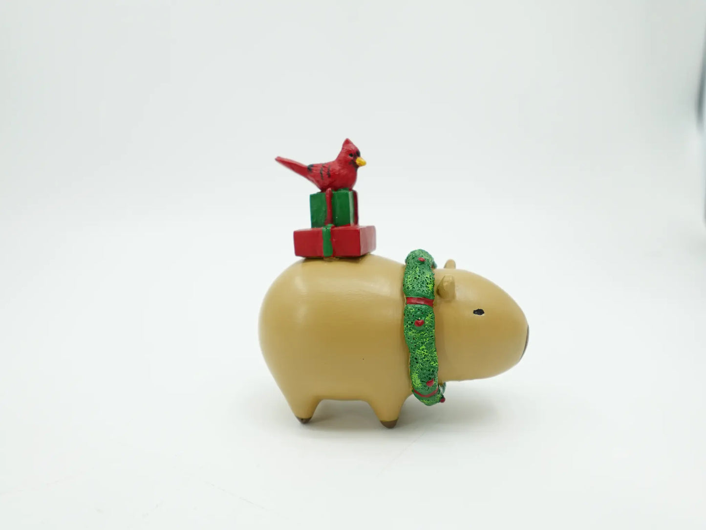 Christmas capybara figurine showing the red cardinal perched on gift boxes, angle view