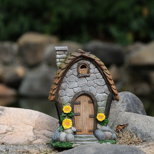 Solar sunflower fairy house displayed in garden among rocks and natural stone backdrop