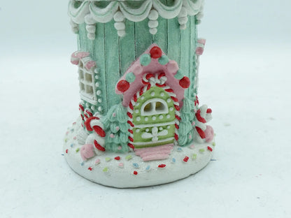 Close-up detail of the green candy door, pink frosting trim, candy-cane pillars and colorful sprinkle base