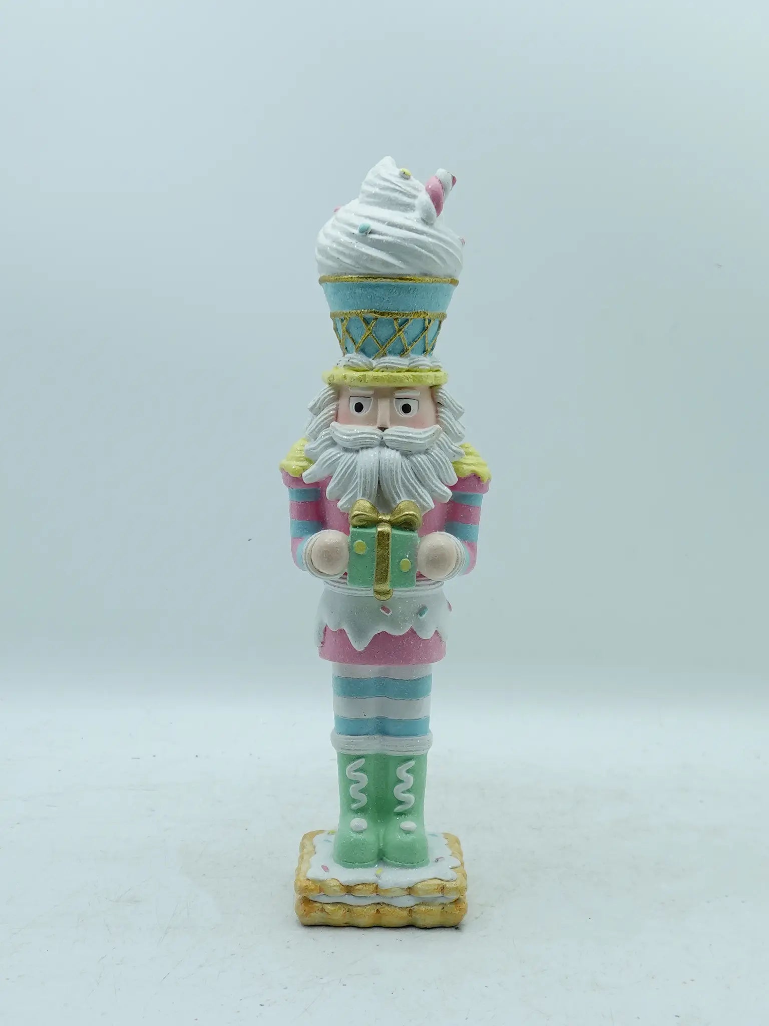 A decorative nutcracker figurine styled as a soldier wearing a light blue and pink ice cream cone uniform, standing on a white background.