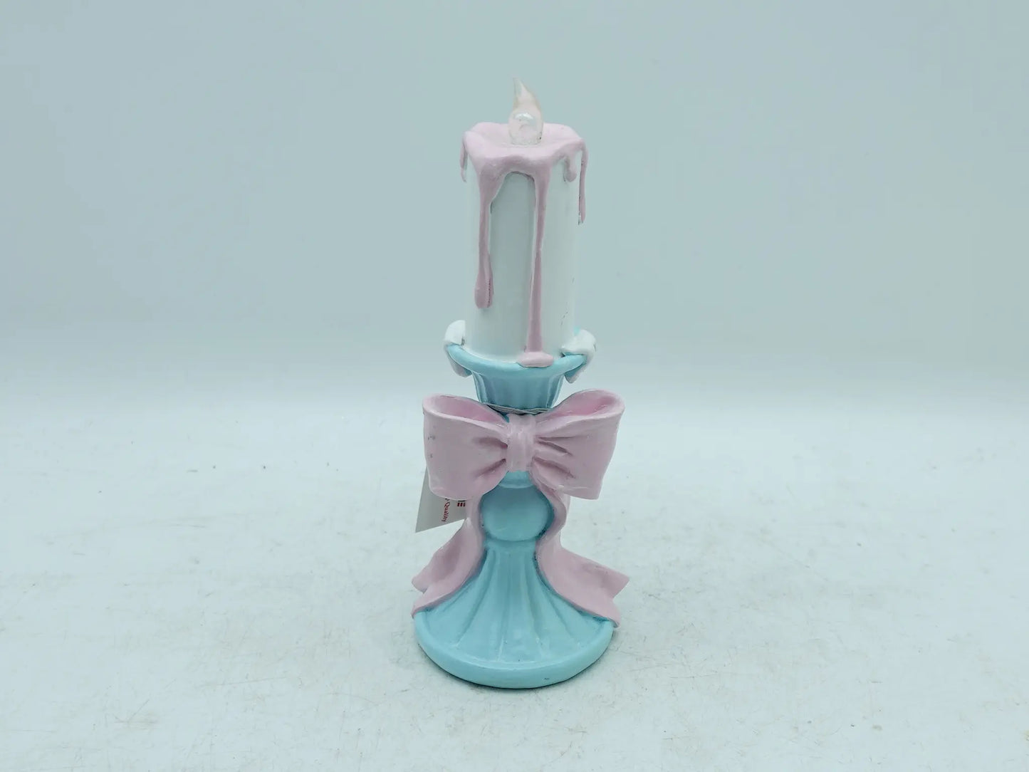 pastel candle holder showing the pink bow, dripping wax effect, and flame tip, front view