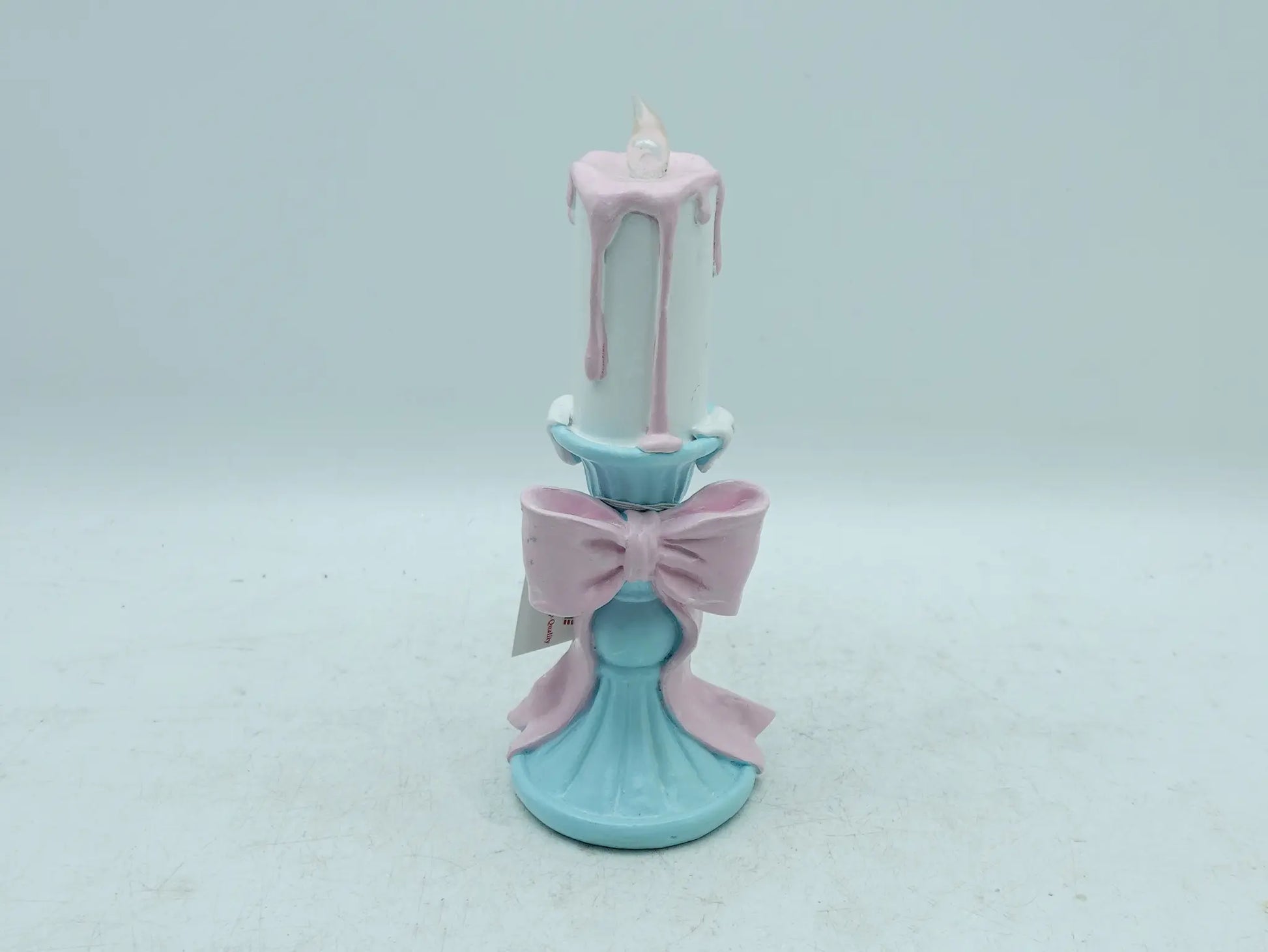 pastel candle holder showing the pink bow, dripping wax effect, and flame tip, front view