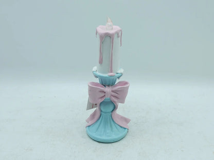 pastel candle holder showing the pink bow, dripping wax effect, and flame tip, front view