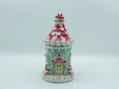 A decorative gingerbread house ornament with a pastel mint green body, photographed against a plain light gray background.