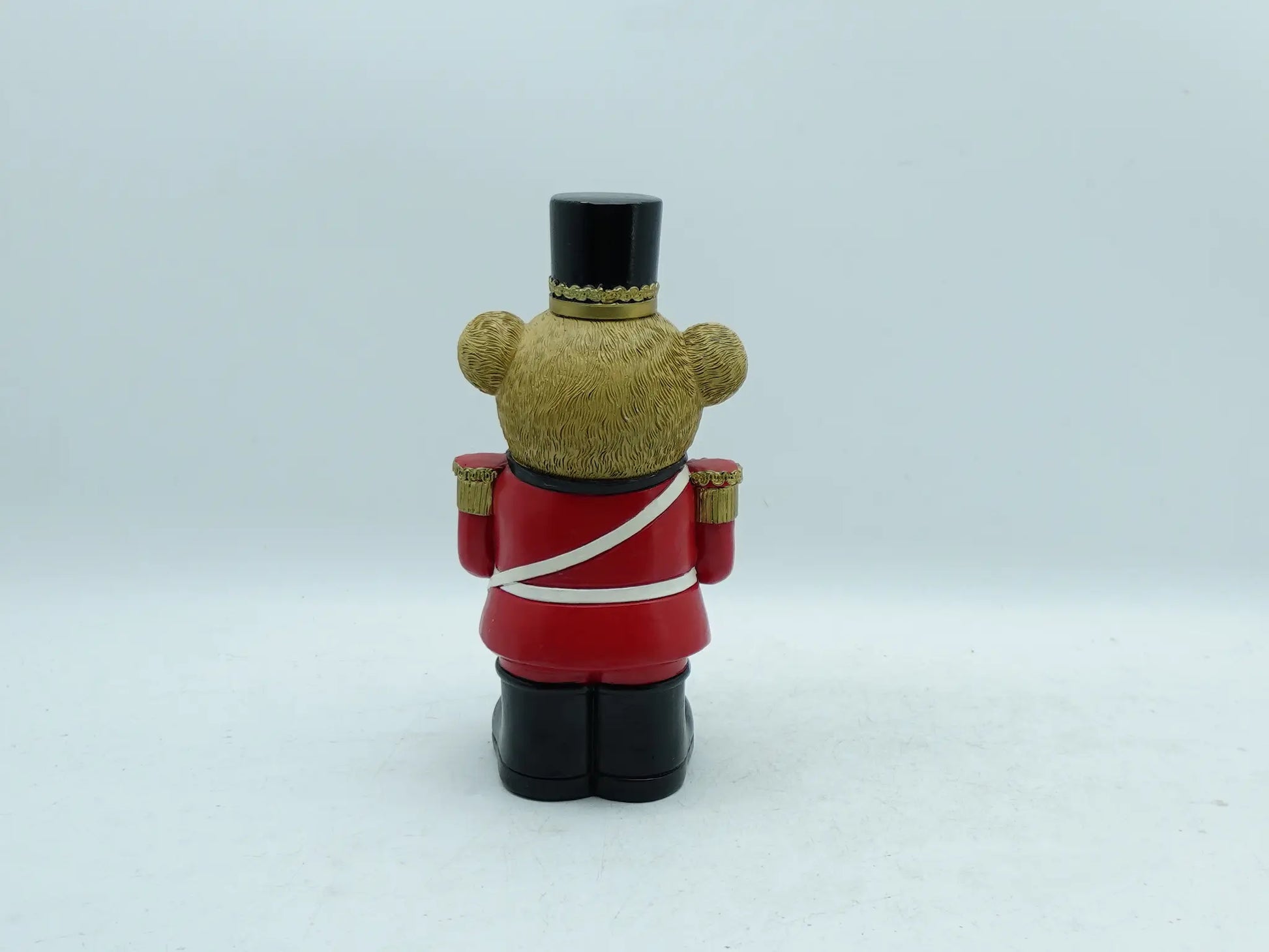 the teddy bear drummer figurine showing the red uniform, white cross strap, and textured bear fur, back view