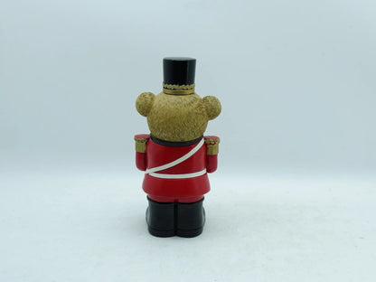 the teddy bear drummer figurine showing the red uniform, white cross strap, and textured bear fur, back view