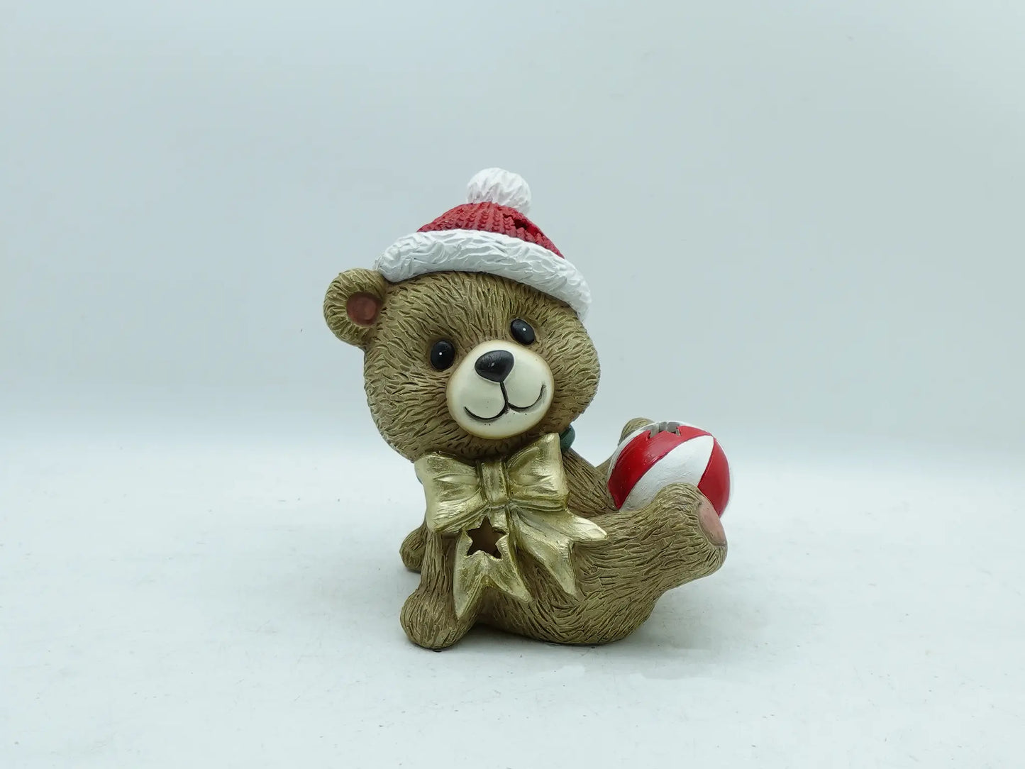 the hand-painted Christmas teddy bear with bauble figurine on clean gray background