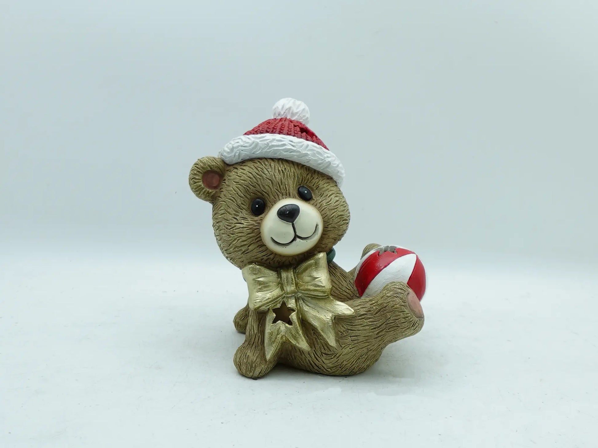 the hand-painted Christmas teddy bear with bauble figurine on clean gray background