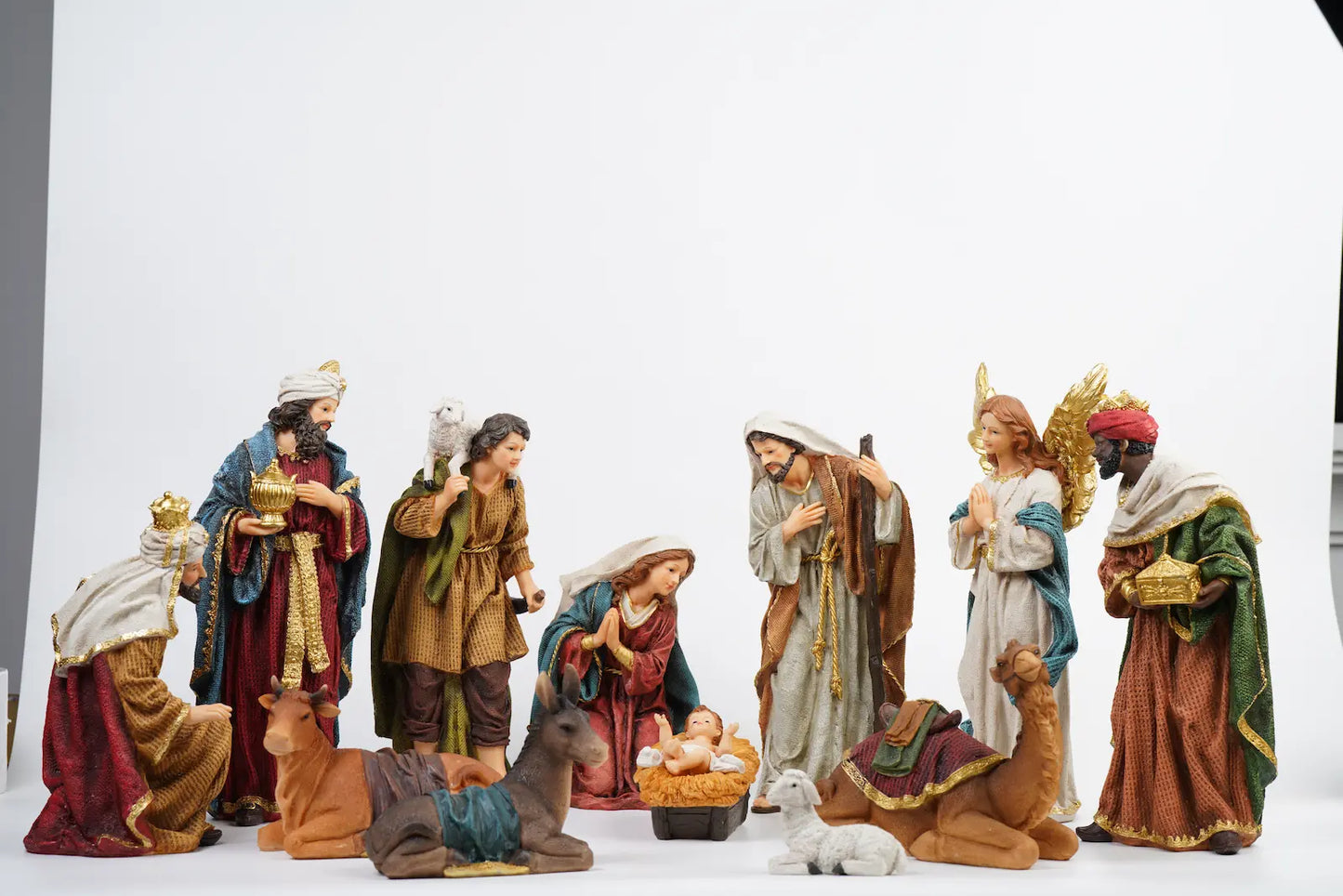 Complete 12-piece colorful nativity scene on white studio background showing full crèche arrangement