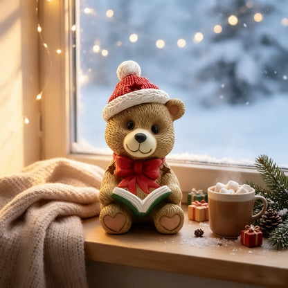 the teddy bear reading book figurine displayed on a windowsill with fairy lights, hot cocoa, blanket, and snowy window view
