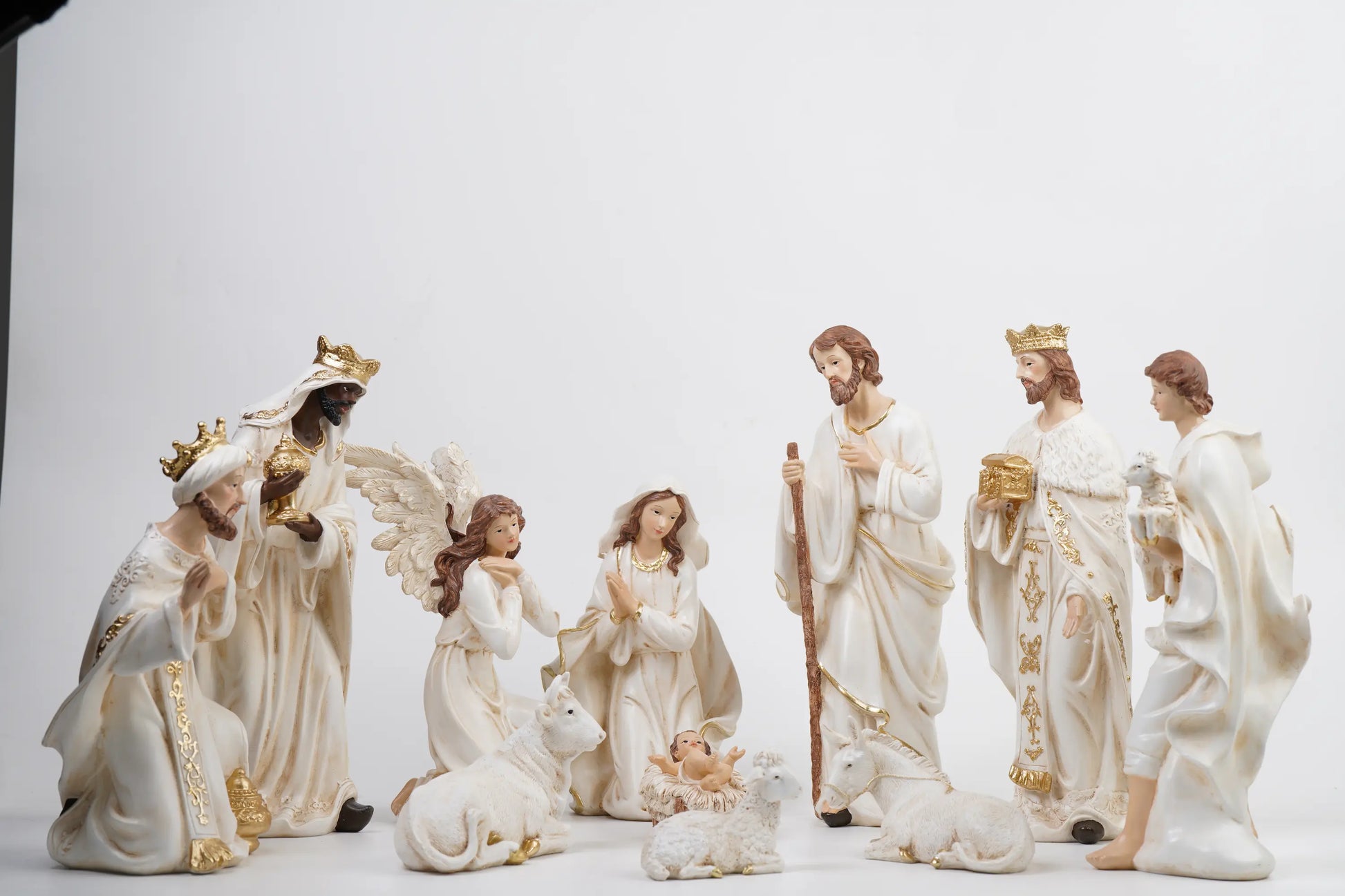 All 11 white and gold nativity figurines on white studio background showing complete crèche arrangement