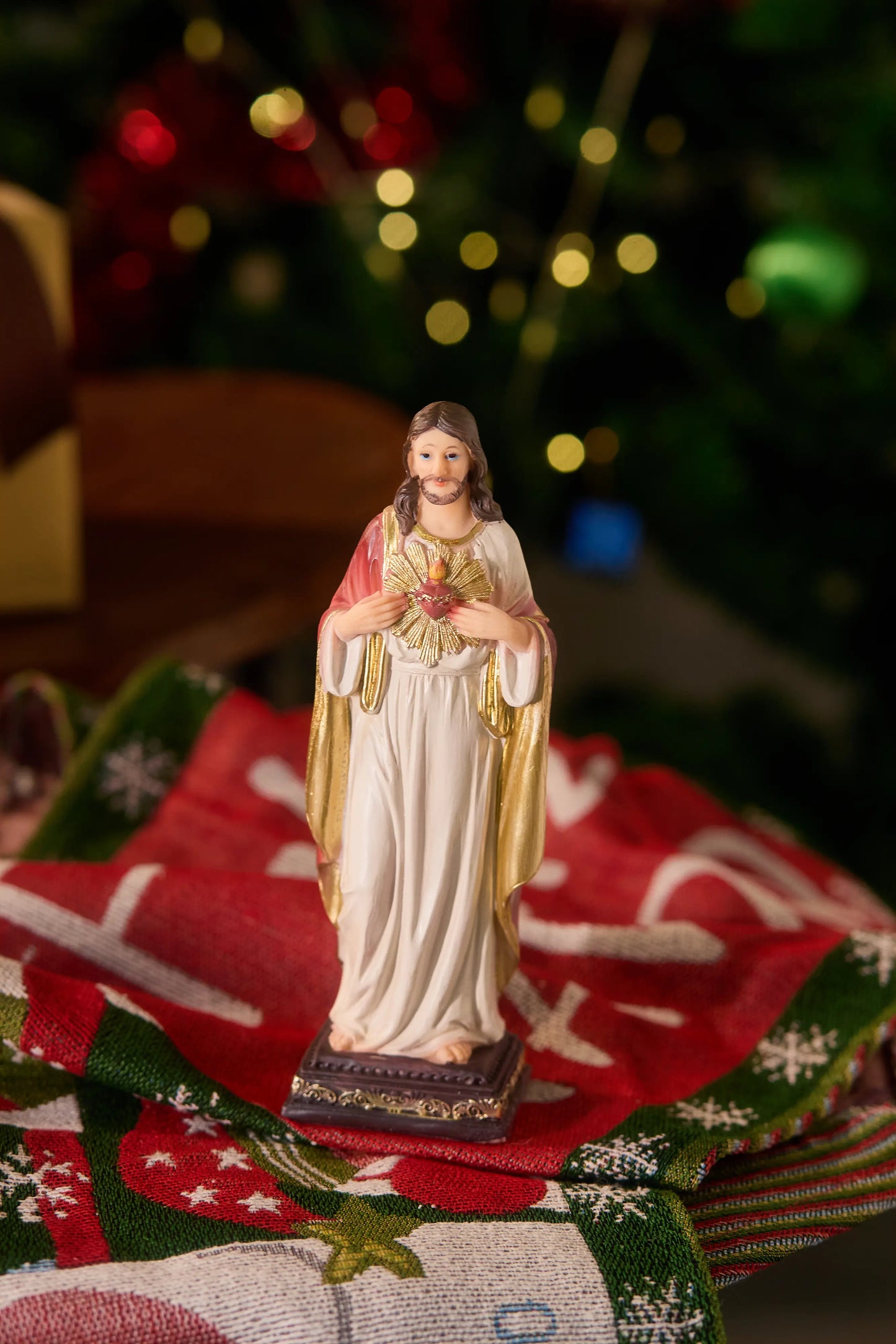 Sacred Heart of Jesus statue displayed on Christmas table runner with festive lights