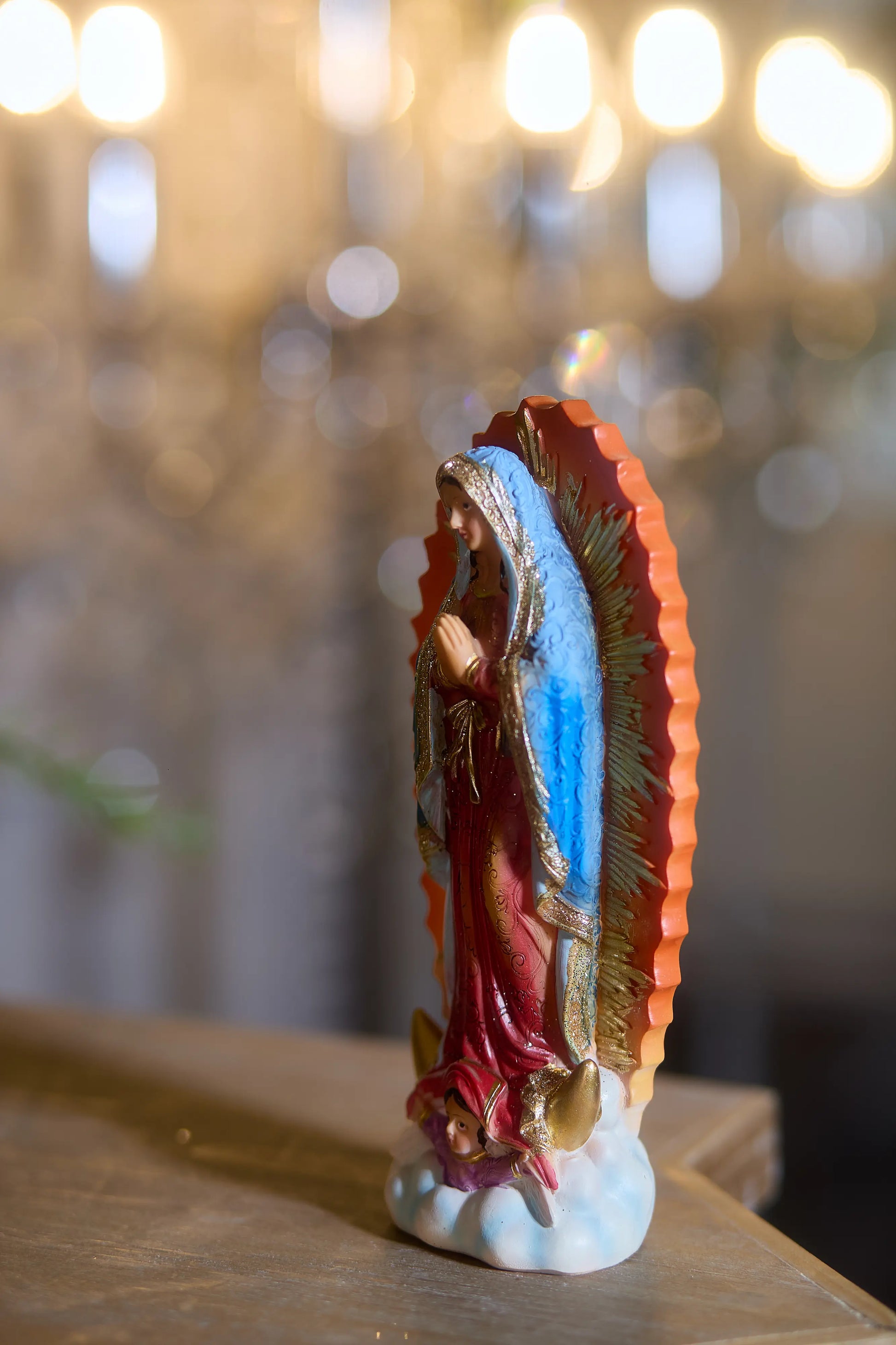 Our Lady of Guadalupe resin statue with golden sunburst halo and praying hands, side view