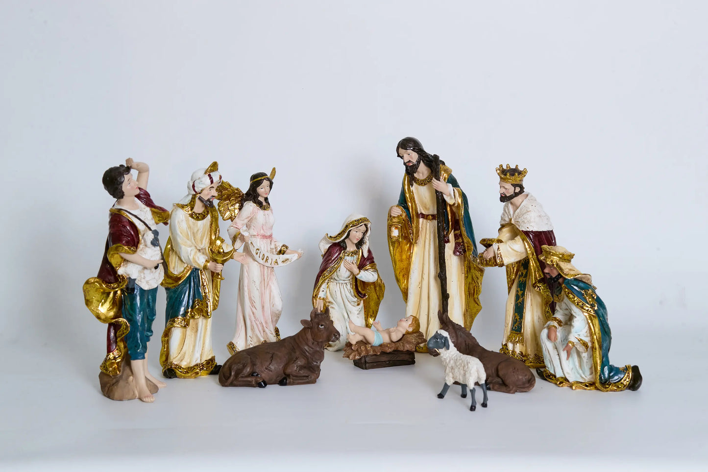 11 nativity figurines on white background including Holy Family, Magi, shepherd, Gloria angel, and stable animals