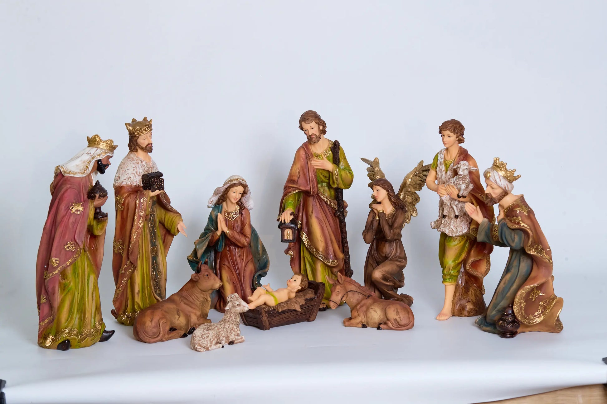 All 11 nativity figurines on white background including Holy Family, Magi, shepherd, kneeling angel, and stable animals