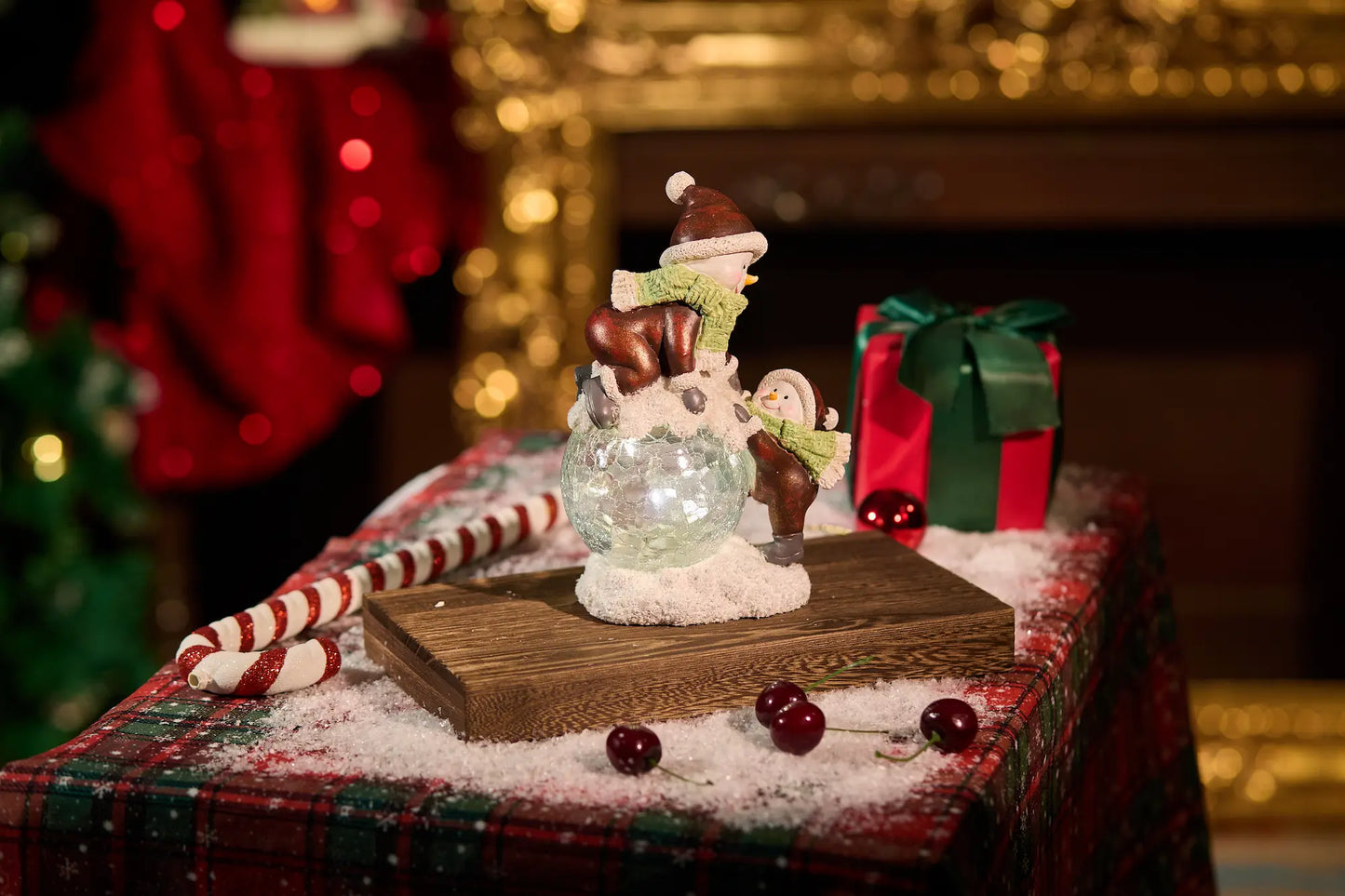 Two snowman figurines with crackle-glass LED snowball on plaid Christmas surface