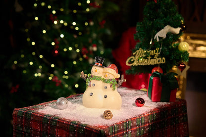 Zayton lighted snowman couple figurine glowing warm — LED glow-through resin Christmas decoration with tree bokeh and gift box background