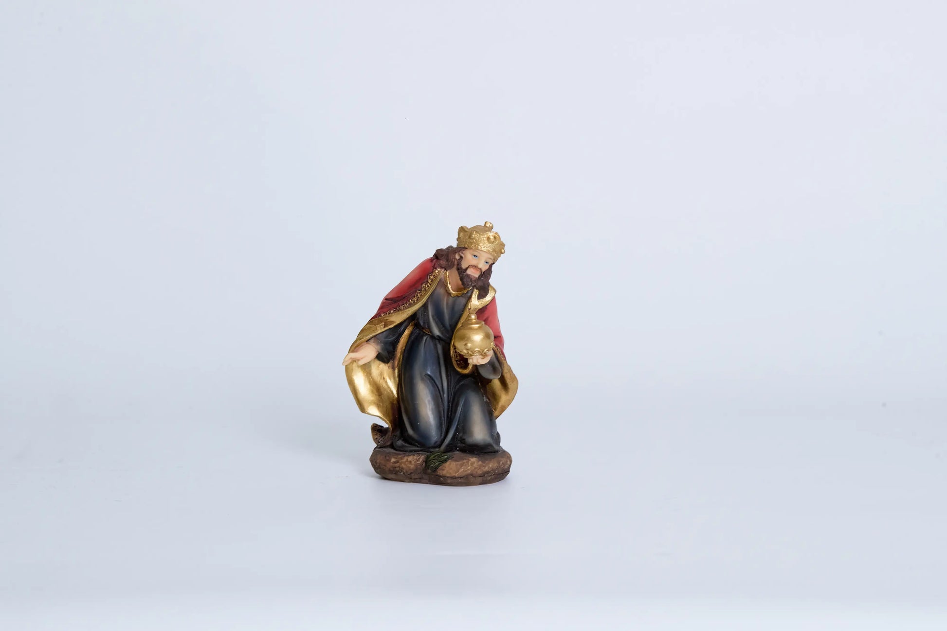 Kneeling Wise Man nativity figurine — Three Kings figure in navy and crimson robes with gold crown presenting golden orb offering, hand-painted resin