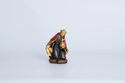 Kneeling Wise Man nativity figurine — Three Kings figure in navy and crimson robes with gold crown presenting golden orb offering, hand-painted resin