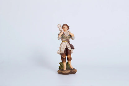 Young shepherd nativity figurine — shepherd boy carrying white lamb on shoulder with gold belt and sheepskin vest, hand-painted resin crèche figure