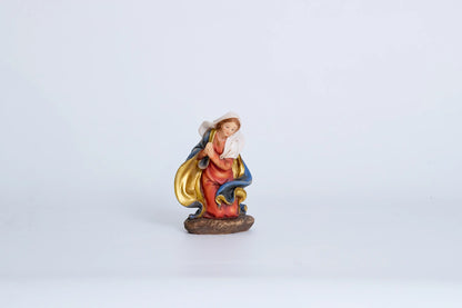 Virgin Mary nativity figurine close-up — kneeling Madonna in crimson robe with blue-and-gold mantle and gold necklace, hand-painted resin devotional figure