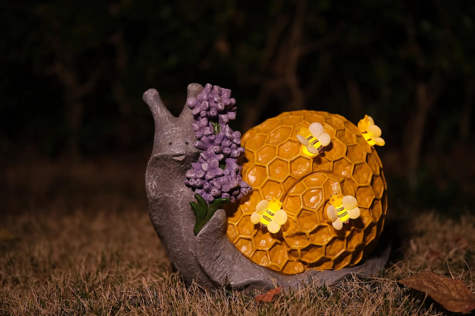 Lighted honeycomb snail yard ornament glowing at night with bee-shaped LED lights