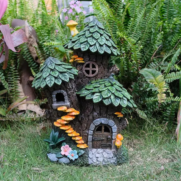Hand-painted solar fairy house in garden setting with ferns and grass