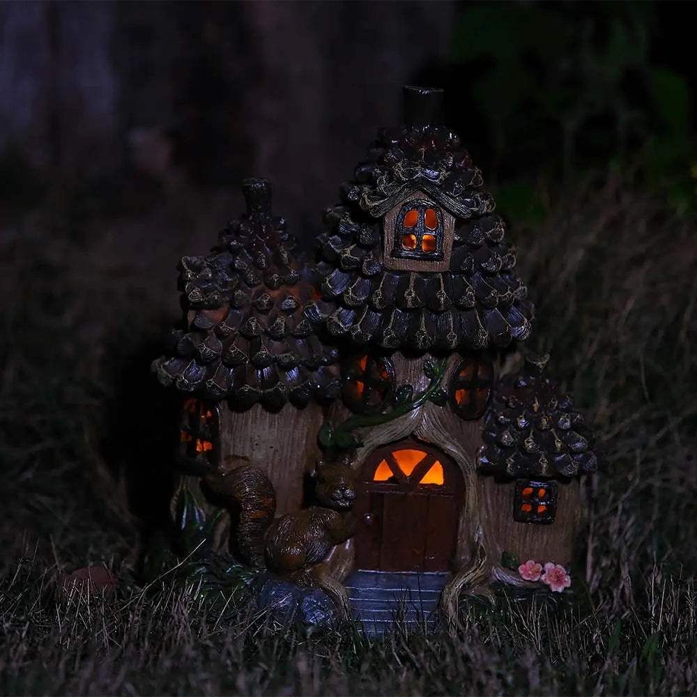 Squirrel fairy house glowing warm amber light at night in outdoor garden