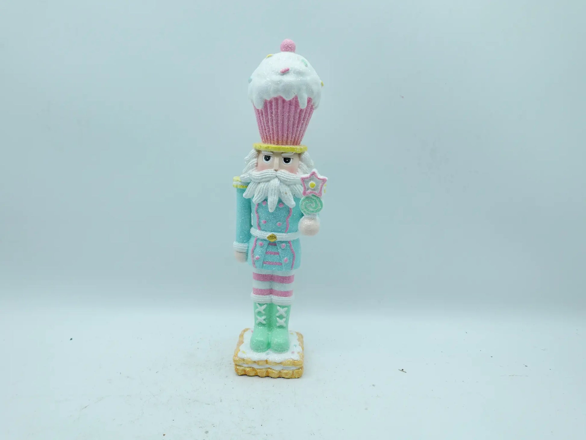 A whimsical cupcake-themed nutcracker figurine standing on a small decorated base against a plain background.