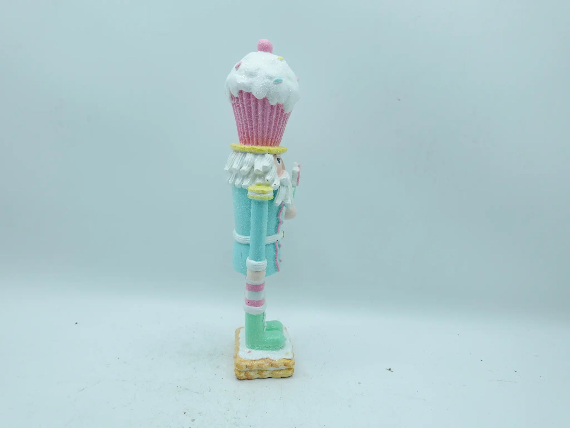 Side view of the nutcracker figurine with pink-and-white striped leggings and cookie base