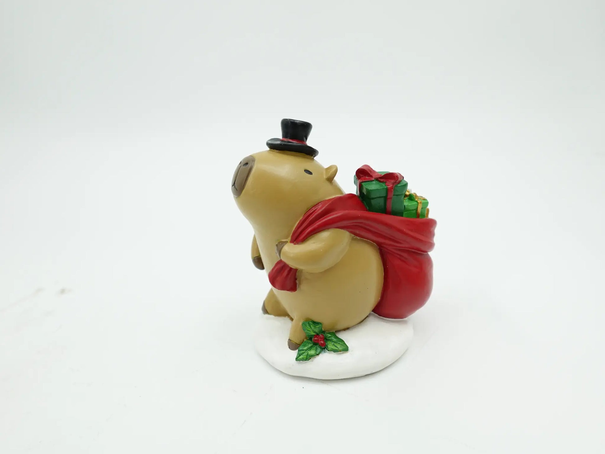 capybara figurine displaying the black top hat and assorted presents inside the red gift bag