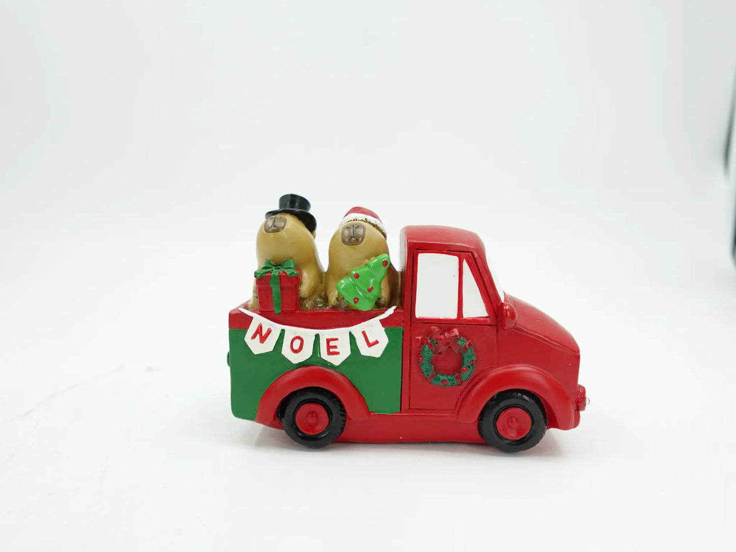 A small Christmas truck figurine with two capybaras in the back, a green gift box, and a banner reading 'NOEL' on a white background.