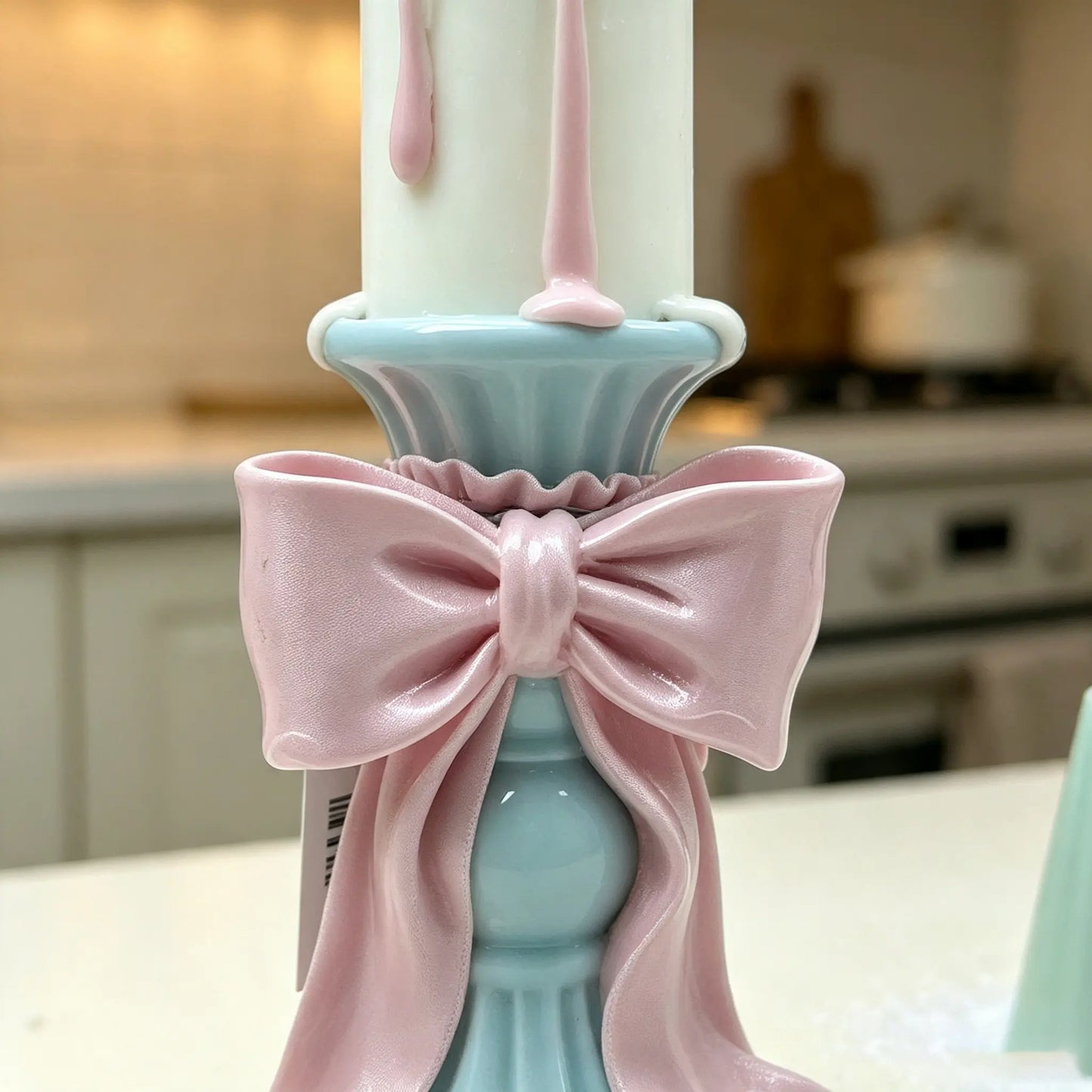 Close-up detail of the glossy pink satin-style bow on the sky-blue candle holder stem