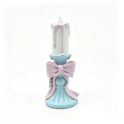resin candle holder figurine with white candle, pink wax drips, and sky-blue pedestal base on white background