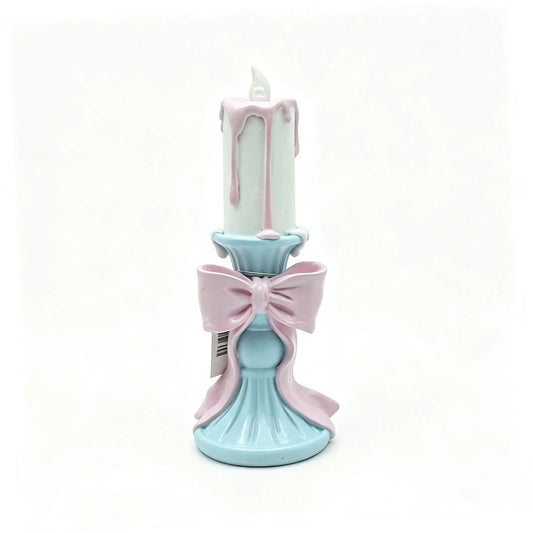 resin candle holder figurine with white candle, pink wax drips, and sky-blue pedestal base on white background