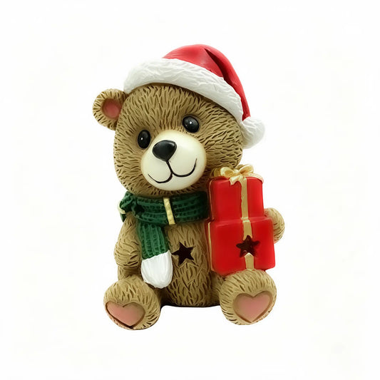 A teddy bear Christmas ornament holding a red gift box with a gold bow, set against a white background.